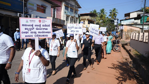The Cancer Awareness March moves through Kumta, with M.I.O. and Sanjeevini Cancer Seva Trust staff holding placards