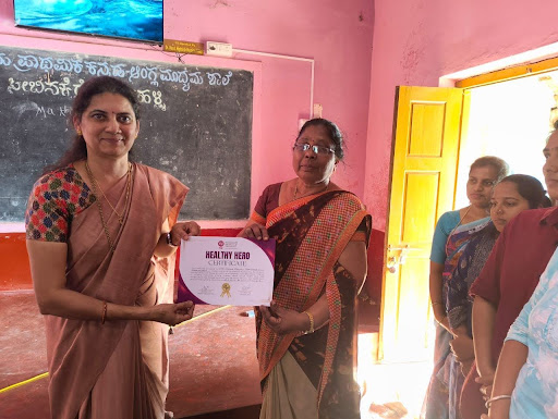 A proud moment as an M.I.O. representative presents the 'Healthy Hero Certificate' to a school staff member at Government Higher Primary School