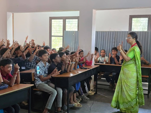 Hands shoot up across the classroom at Sri Vidyavilasa School, Polali — students eagerly participate in M.I.O.'s Healthy Hero session, proving that health education works best when it feels like a conversation, not a lecture.
